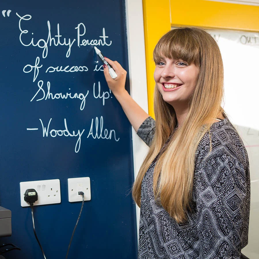 Woman writing on clear whiteboard paint blue office wall
